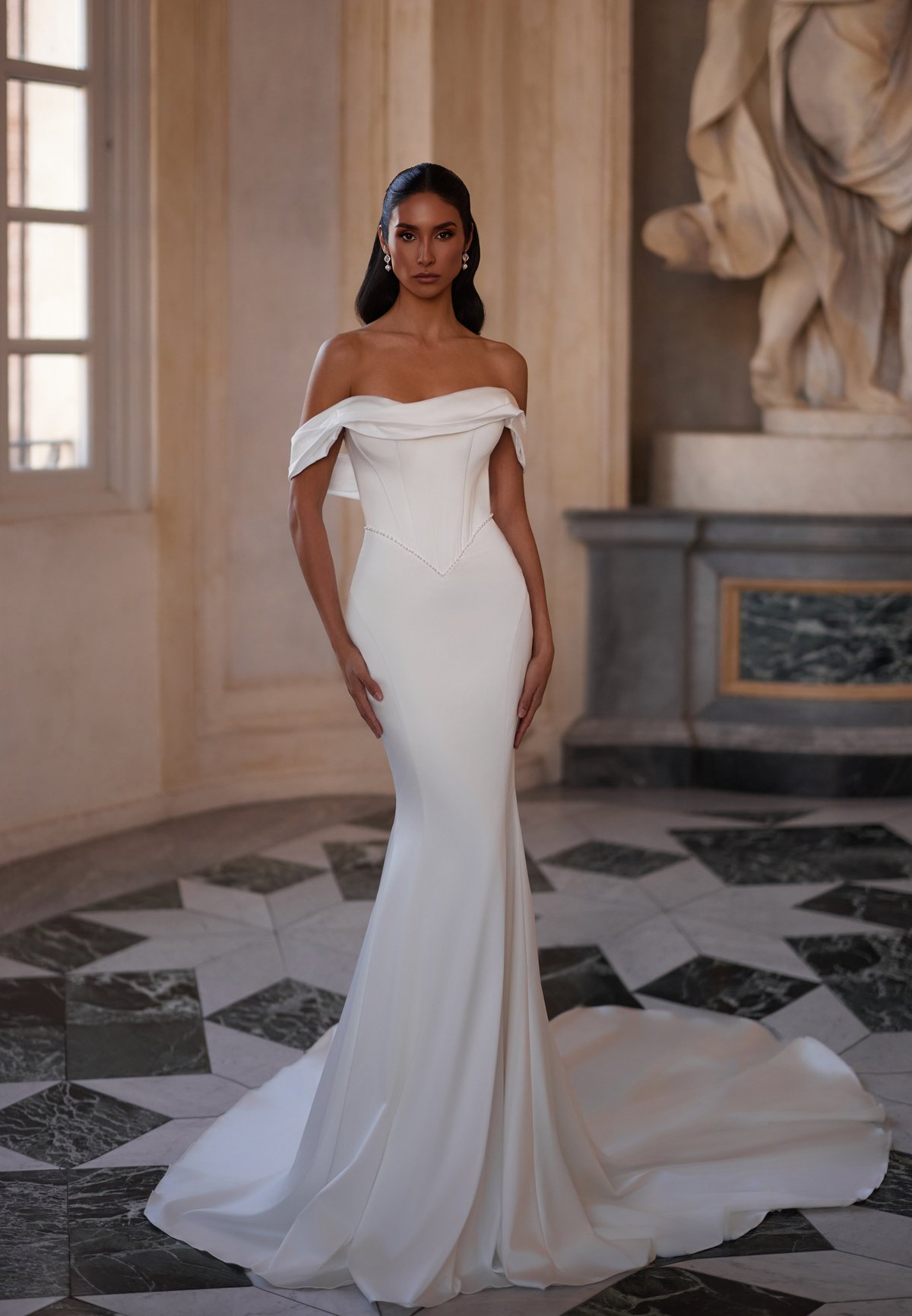 Woman wearing elegant white off-shoulder wedding gown with flowing train in classical interior with marble floor and statue.